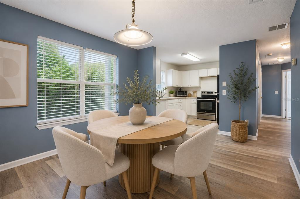 A dining area with a round wooden table, four chairs, and an adjacent white kitchen — 4532 HUPPEL AVENUE, ORLANDO, FL