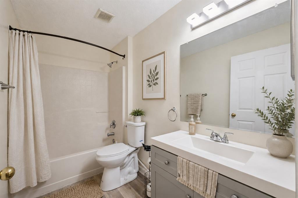 A bathroom features a gray vanity, a white countertop, a toilet, and a shower-tub combo — 4532 HUPPEL AVENUE, ORLANDO, FL
