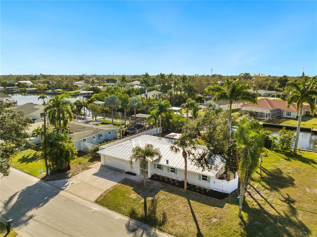 An aerial view shows a single-story house with a metal roof near a canal — 6911 9TH AVENUE NW, BRADENTON, FL