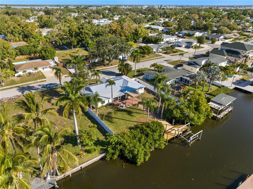 An aerial view shows a waterfront house with a metal roof and a private dock — 6911 9TH AVENUE NW, BRADENTON, FL