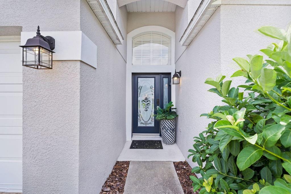 A front entryway features a dark door with a glass insert, a transom window, and sconces — 2916 BLOOMING ALAMANDA LOOP, KISSIMMEE, FL