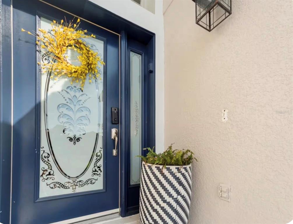 A blue front door with a decorative glass insert and a yellow wreath stands outside — 2916 BLOOMING ALAMANDA LOOP, KISSIMMEE, FL