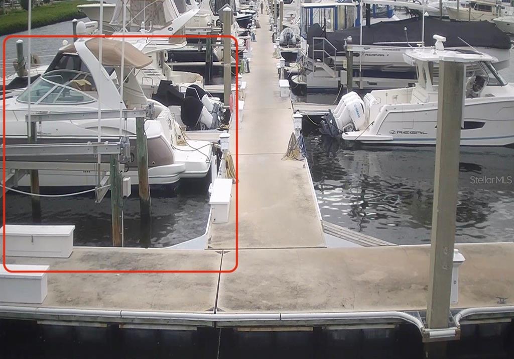 A boat is docked at a concrete pier with a boat lift in a marina — 102 RIVIERA DUNES WAY UNIT N-1, PALMETTO, FL