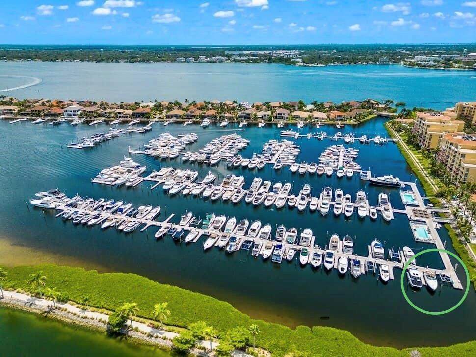 An aerial view shows a marina with numerous docked boats and a large residential complex — 102 RIVIERA DUNES WAY UNIT N-1, PALMETTO, FL