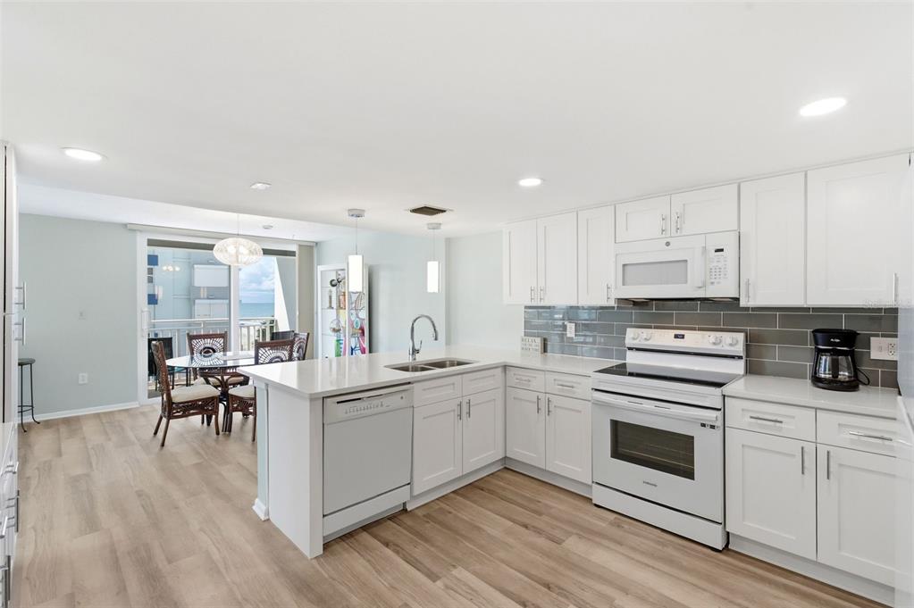 A bright kitchen features white cabinets, quartz countertops, and a gray tile backsplash — 17408 GULF BOULEVARD UNIT 403, REDINGTON SHORES, FL