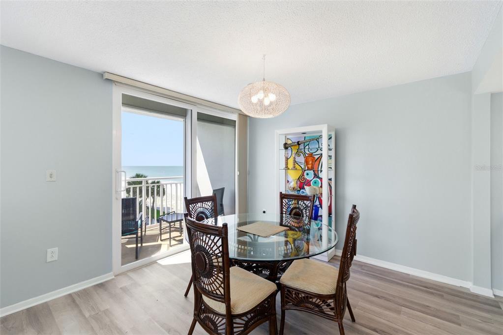 A dining area with a glass table, wicker chairs, and a sliding door to a balcony — 17408 GULF BOULEVARD UNIT 403, REDINGTON SHORES, FL