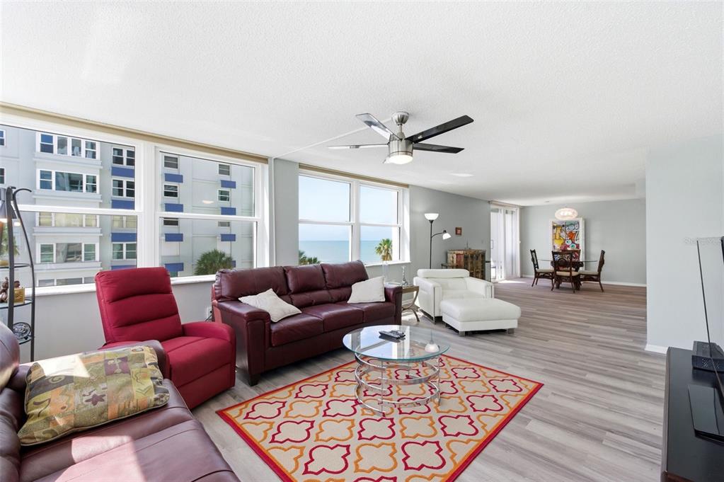 A living room with a red sofa, a white chaise, and a view of the ocean — 17408 GULF BOULEVARD UNIT 403, REDINGTON SHORES, FL