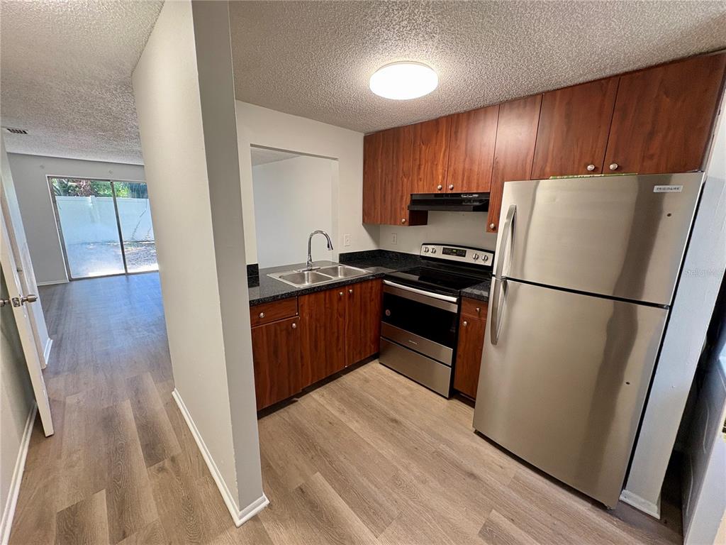A galley kitchen features wood cabinets, stainless steel appliances, and dark countertops — 409 57TH AVENUE DRIVE E UNIT A, BRADENTON, FL