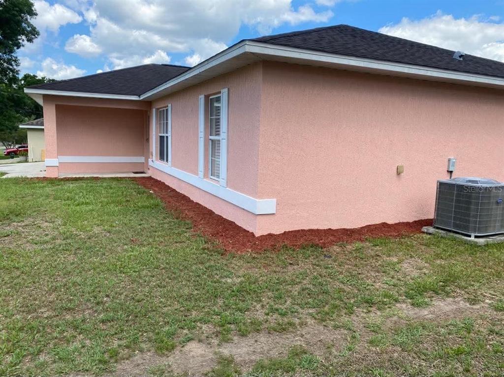 The exterior of a pink stucco house features a covered entryway and an air conditioning unit — 785 NW 67TH STREET, OCALA, FL
