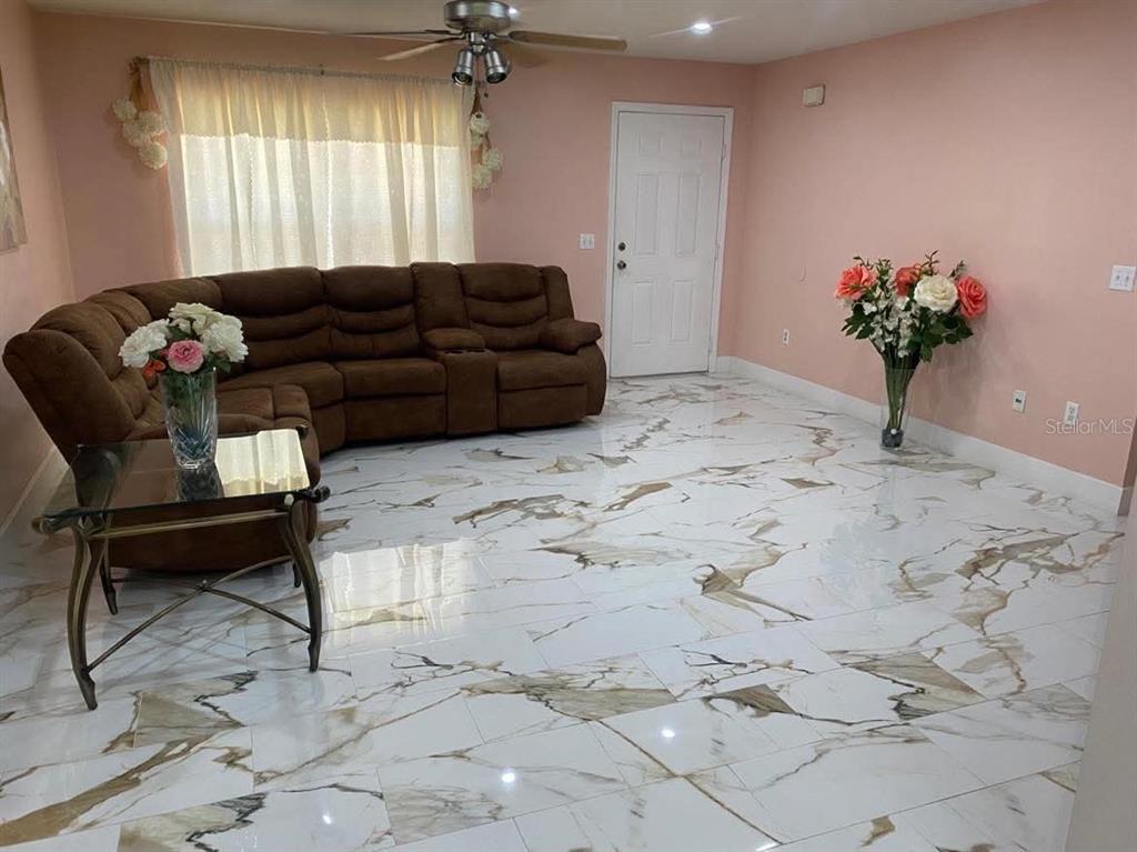 A living room features a brown sectional sofa, marble-patterned tile flooring, and pink walls — 785 NW 67TH STREET, OCALA, FL
