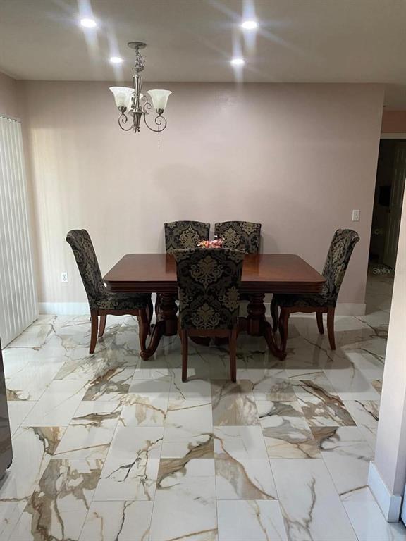 A dining room features a wooden table, four patterned chairs, and white marble-look tile flooring — 785 NW 67TH STREET, OCALA, FL