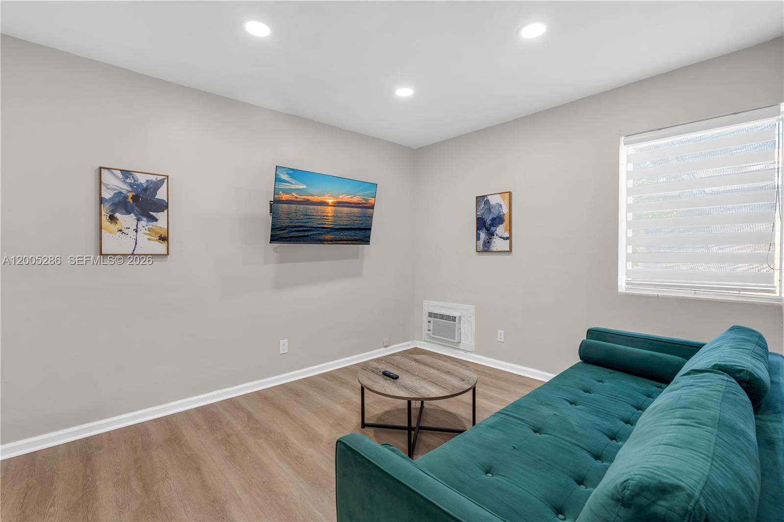A living room features a teal sofa, a round coffee table, and a wall-mounted television — 10006 E Bay Harbor Dr # 15, Bay Harbor Islands FL 33154, BAY HARBOR ISLANDS, FL