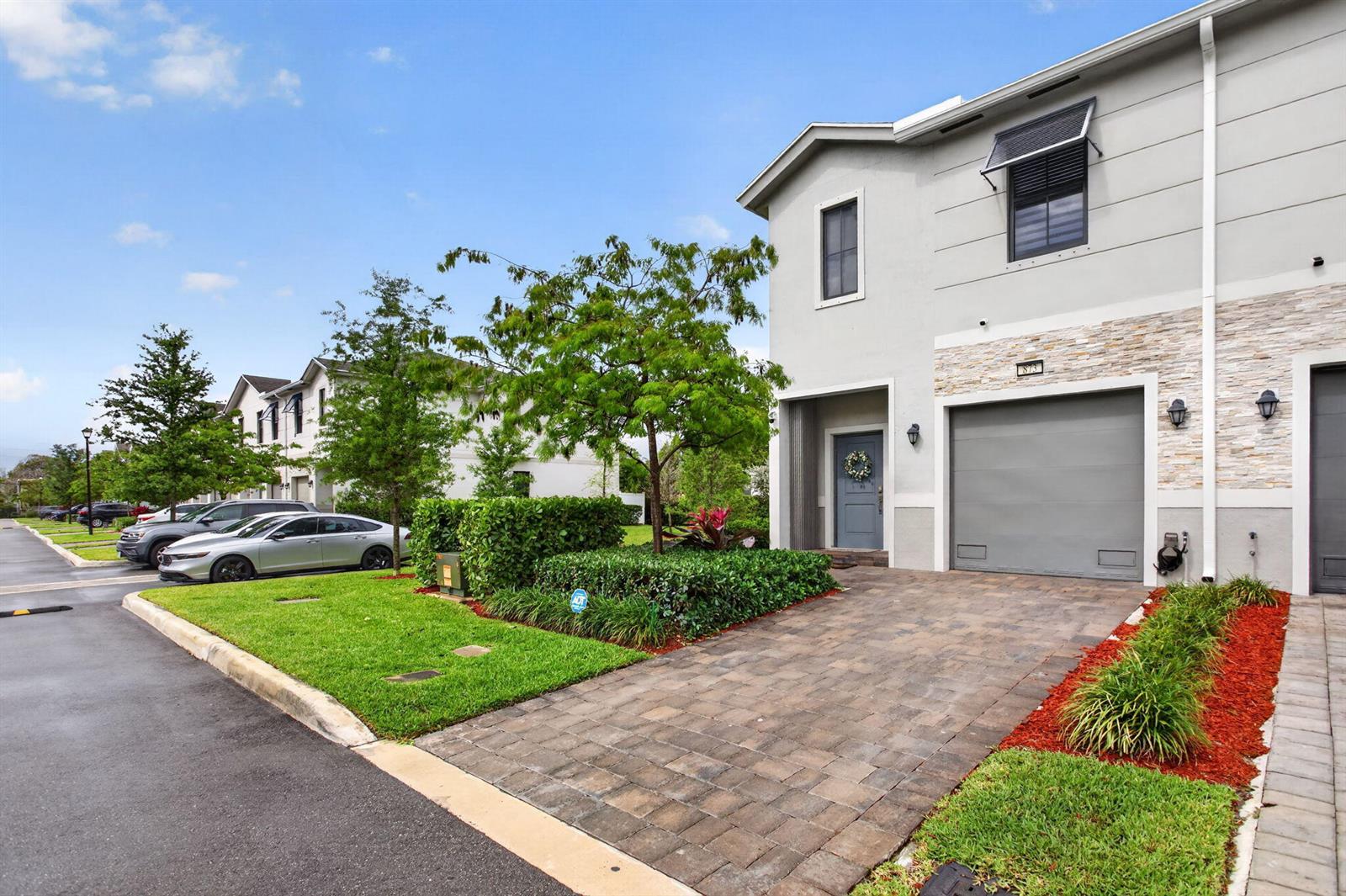 A two-story townhouse with a gray garage, stone facade, and a paved driveway — 873 NW 3rd Way, Pompano Beach FL 33060, POMPANO BEACH, FL
