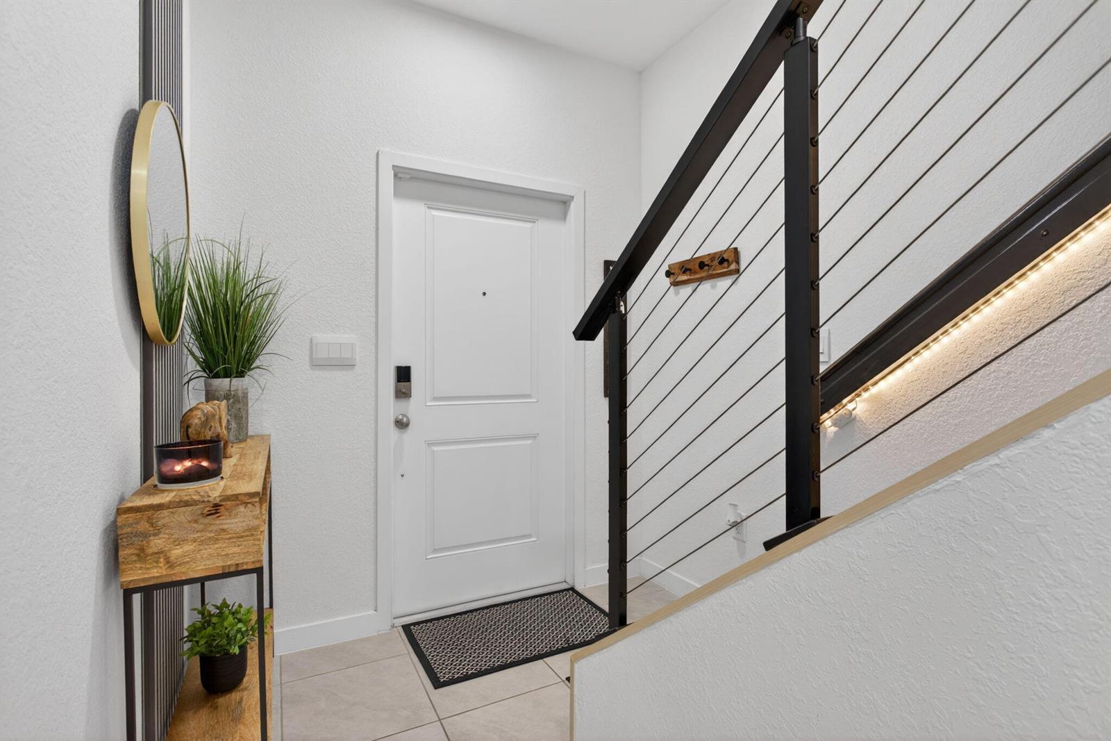 An entryway features a white door, a wooden console table, and a staircase with cable railings — 873 NW 3rd Way, Pompano Beach FL 33060, POMPANO BEACH, FL