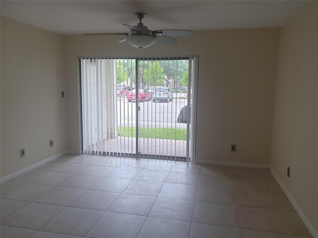 An empty room with beige tile flooring, a ceiling fan, and sliding glass patio doors — 520 S Park Road # 12, Hollywood FL 33021, HOLLYWOOD, FL