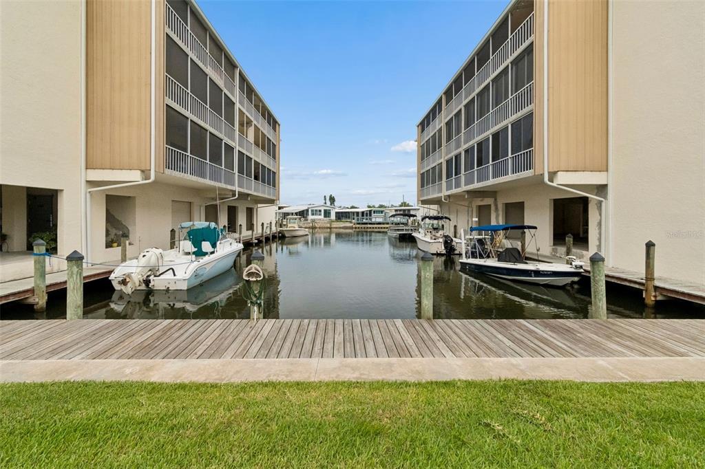 A canal view between two multi-story apartment buildings with private boat slips and docks — 1714 69TH AVENUE W UNIT C401, BRADENTON, FL