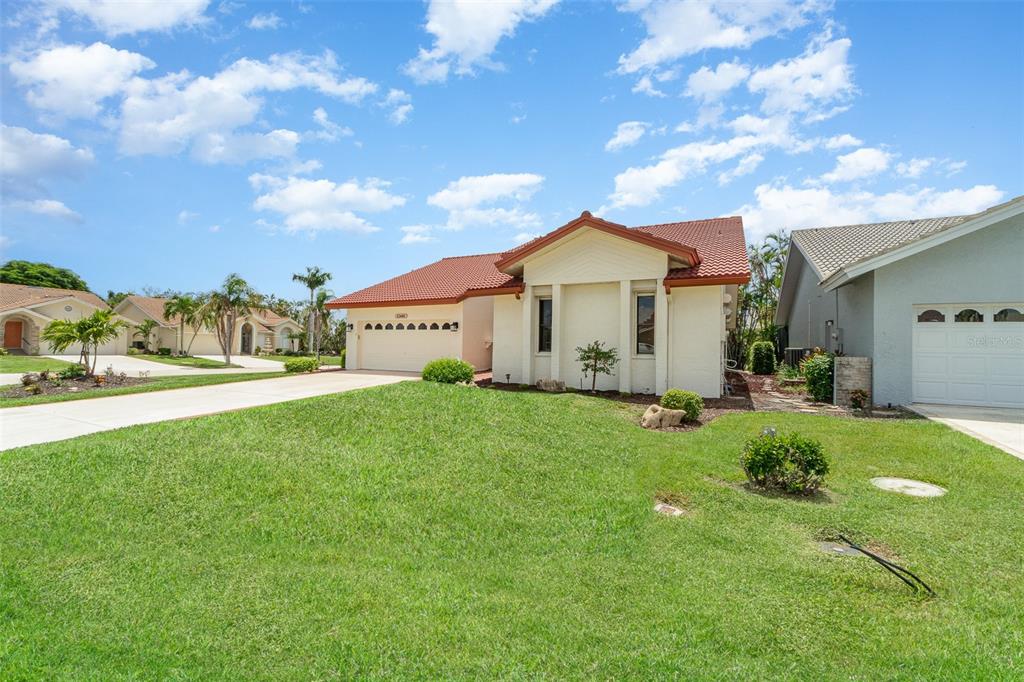 A single-story house with a red tile roof and a concrete driveway under a blue sky — 12601 KELLY PALM DRIVE, FORT MYERS, FL