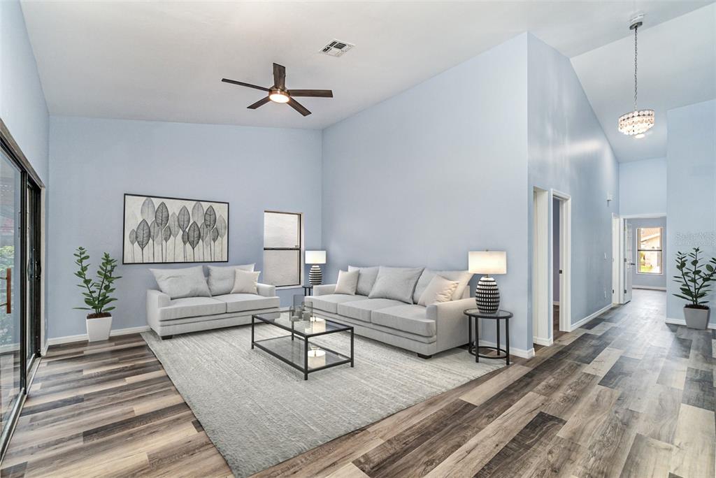 A living room features light blue walls, wood-look flooring, two gray sofas, and a ceiling fan — 12601 KELLY PALM DRIVE, FORT MYERS, FL