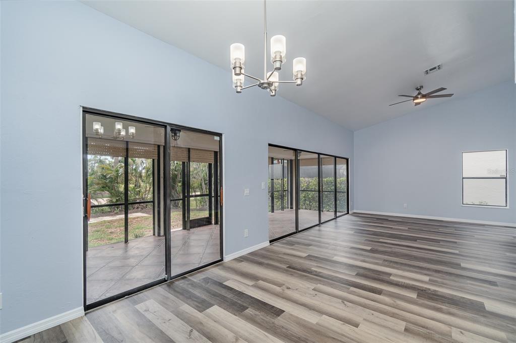 A spacious room with light blue walls, wood-look flooring, a chandelier, and sliding glass doors — 12601 KELLY PALM DRIVE, FORT MYERS, FL