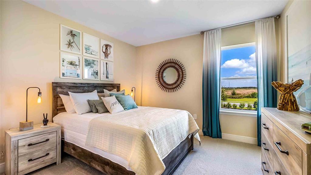 A bedroom features a queen bed, wooden nightstand, dresser, and blue ombre curtains — 18211 THISTLEBERRY PLACE, LAKEWOOD RANCH, FL