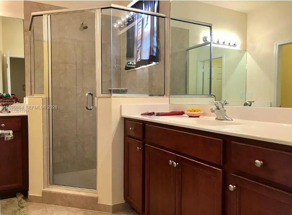 A bathroom features a glass-enclosed shower, a wooden vanity with a sink, and a mirror — 5919 NW 56th Pl, Tamarac FL 33319, TAMARAC, FL
