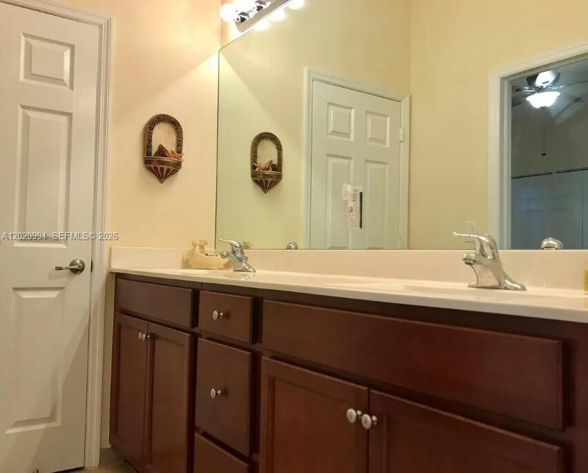 A bathroom features a double vanity with dark wood cabinets and a large wall mirror — 5919 NW 56th Pl, Tamarac FL 33319, TAMARAC, FL