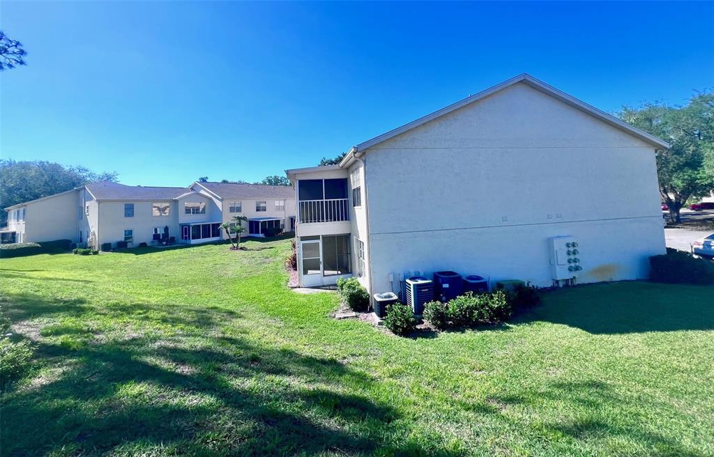 A grassy lawn sits beside a multi-story building and a covered parking structure — 7828 HARDWICK DRIVE UNIT 927, NEW PORT RICHEY, FL