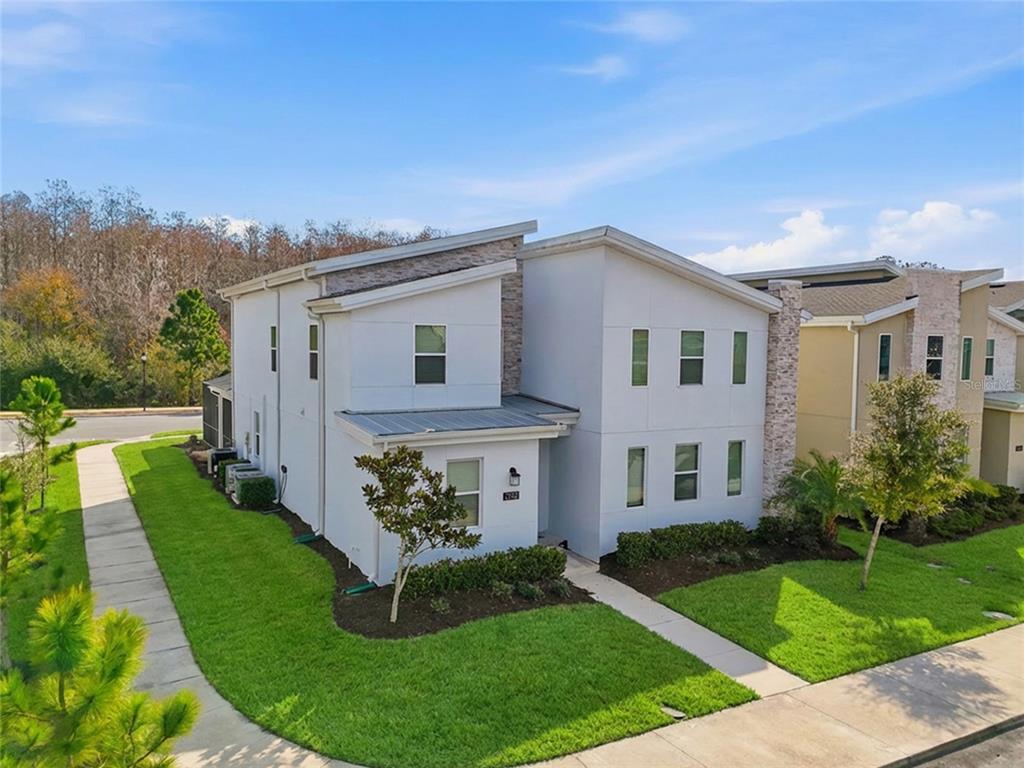 A two-story modern townhouse with white stucco siding and a stone accent wall — 2706 OXYMORON WAY, KISSIMMEE, FL