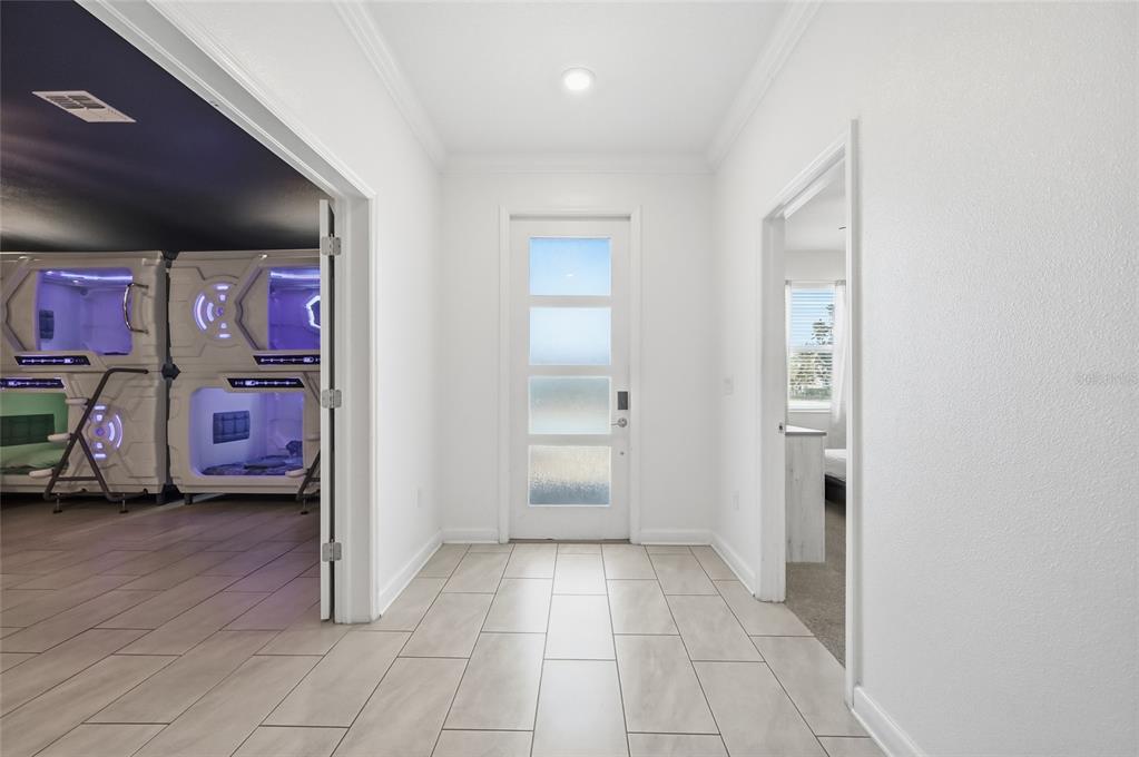 A hallway with tile flooring leads to a front door flanked by two doorways — 2706 OXYMORON WAY, KISSIMMEE, FL