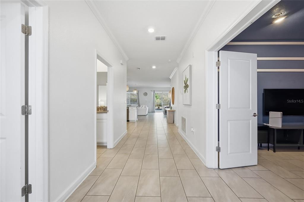 A hallway with tile flooring leads to an open living area with a sliding door — 2706 OXYMORON WAY, KISSIMMEE, FL