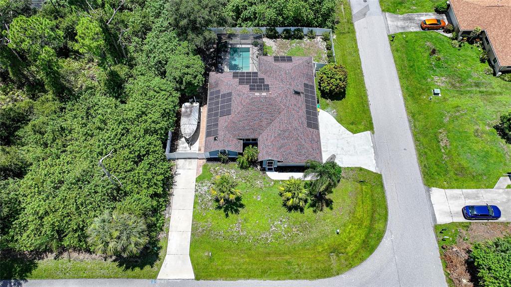 An aerial view shows a house with a pool, solar panels, and a boat parked outside — 1632 AMSTEAD STREET, PORT CHARLOTTE, FL