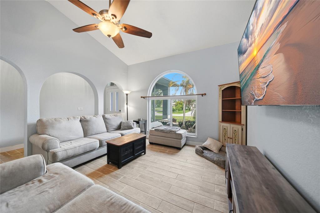 A living room features a vaulted ceiling, arched doorways, tile flooring, and a large window — 1632 AMSTEAD STREET, PORT CHARLOTTE, FL