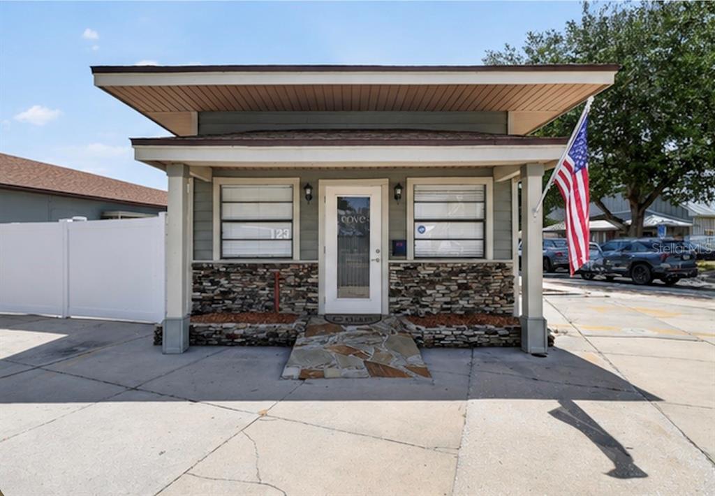 A small, single-story building features a stone facade, a covered porch, and an American flag — 119 MAIN STREET, AUBURNDALE, FL