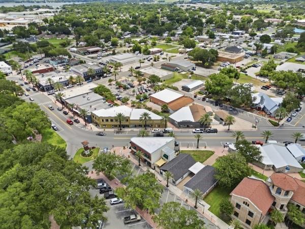 An aerial view of a town center with commercial buildings, parking lots, and surrounding trees — 119 MAIN STREET, AUBURNDALE, FL