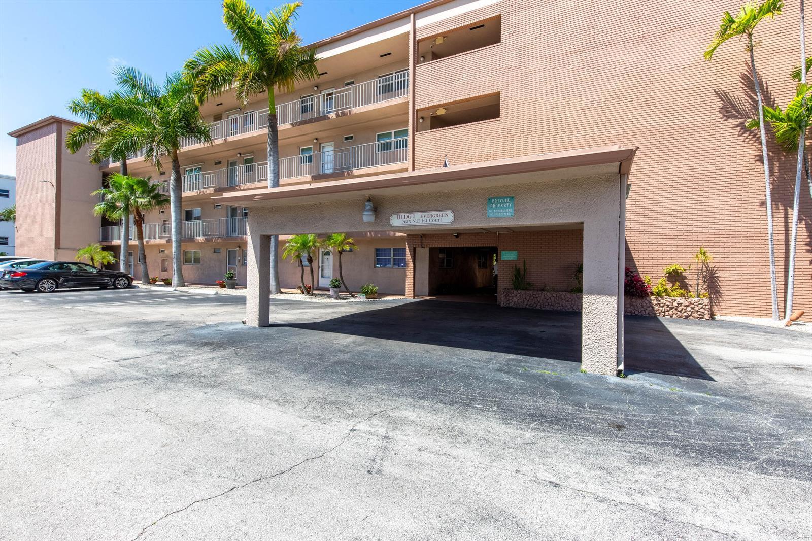 A multi-story brick apartment building features a covered entryway and palm trees in front — 2615 NE 1st Court # 411, Boynton Beach FL 33435, BOYNTON BEACH, FL