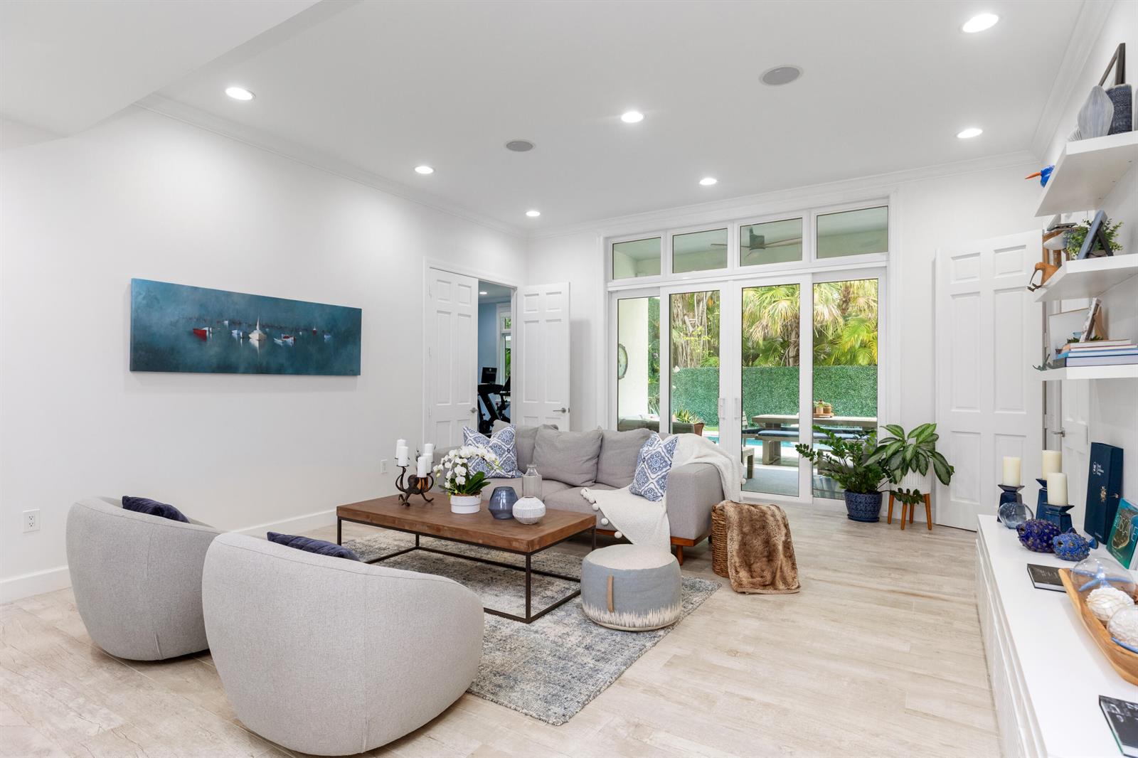 A bright living room features a grey sofa, two armchairs, and glass doors to a patio — 24 Grand Bay Estates Circle, Key Biscayne FL 33149, KEY BISCAYNE, FL