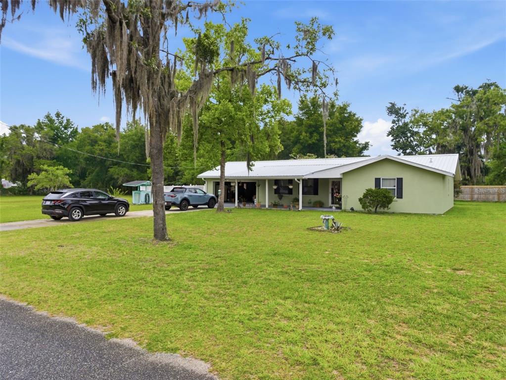 A light green, single-story house with a metal roof sits on a large grassy lot — 334 7TH WAY, INTERLACHEN, FL