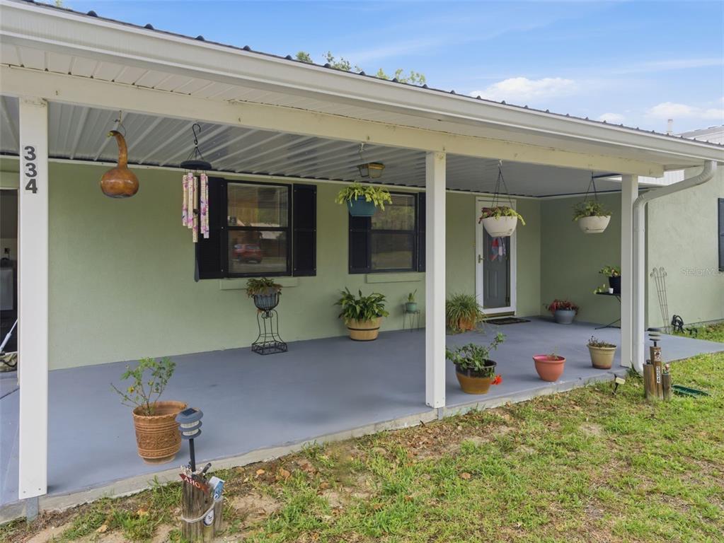 A covered front porch with a gray floor, light green walls, and several potted plants — 334 7TH WAY, INTERLACHEN, FL