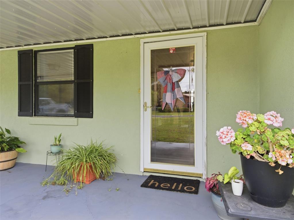 A light green exterior wall features a front door with a bow and a welcome mat — 334 7TH WAY, INTERLACHEN, FL