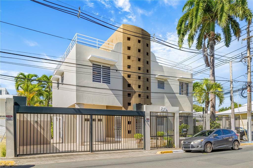 A two-story house with a tan central tower and a gated driveway under a blue sky — 1858 MCLEARY, SAN JUAN, PR
