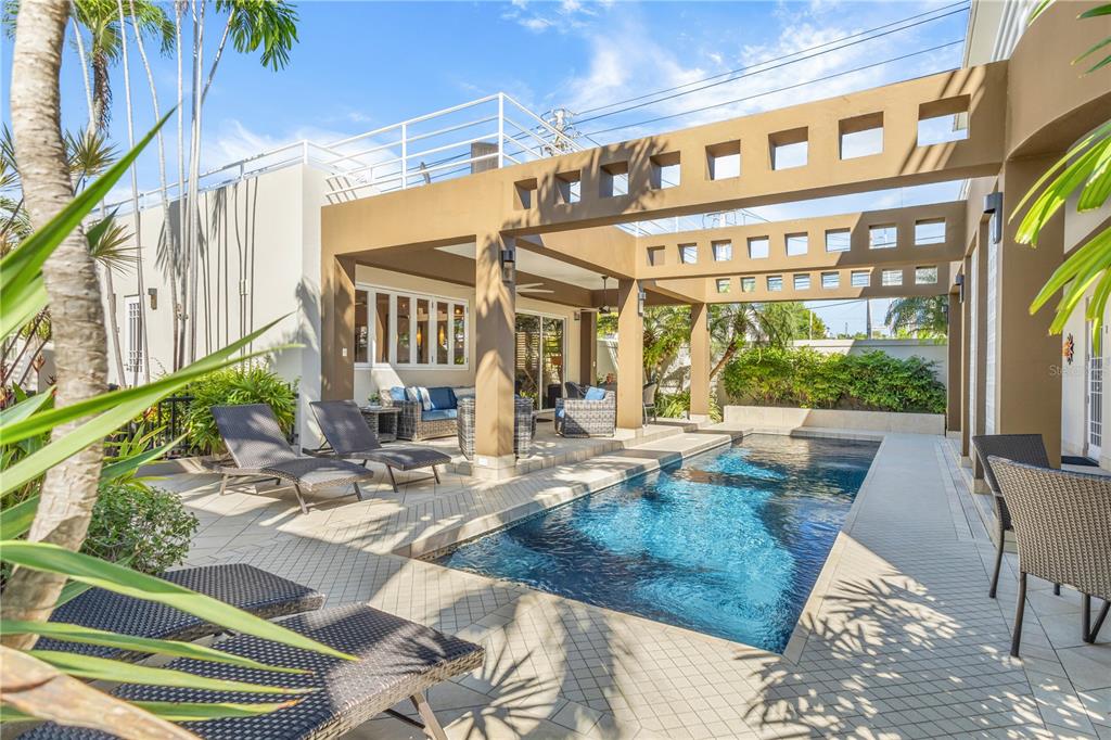 A swimming pool sits on a tiled patio beneath a modern, open-air pergola structure — 1858 MCLEARY, SAN JUAN, PR
