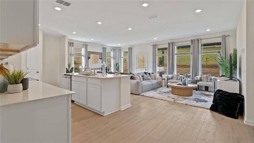 An open-concept kitchen and living room featuring light wood floors and large windows — 2234 JENNIO DRIVE, HAINES CITY, FL