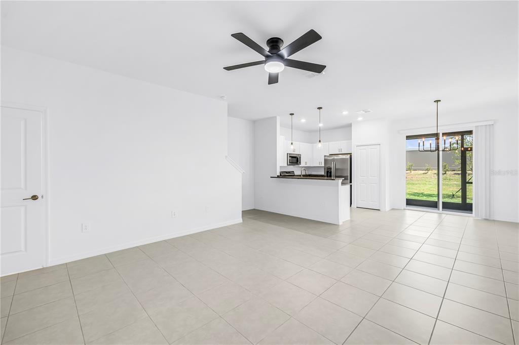 An open-concept living and kitchen area with white walls, tile flooring, and a ceiling fan — 9305 BONITA MAR DRIVE, PARRISH, FL