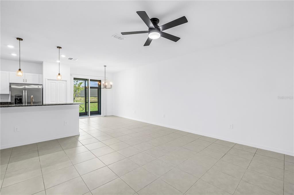 An open-concept living area features light tile flooring, white walls, and a ceiling fan — 9305 BONITA MAR DRIVE, PARRISH, FL