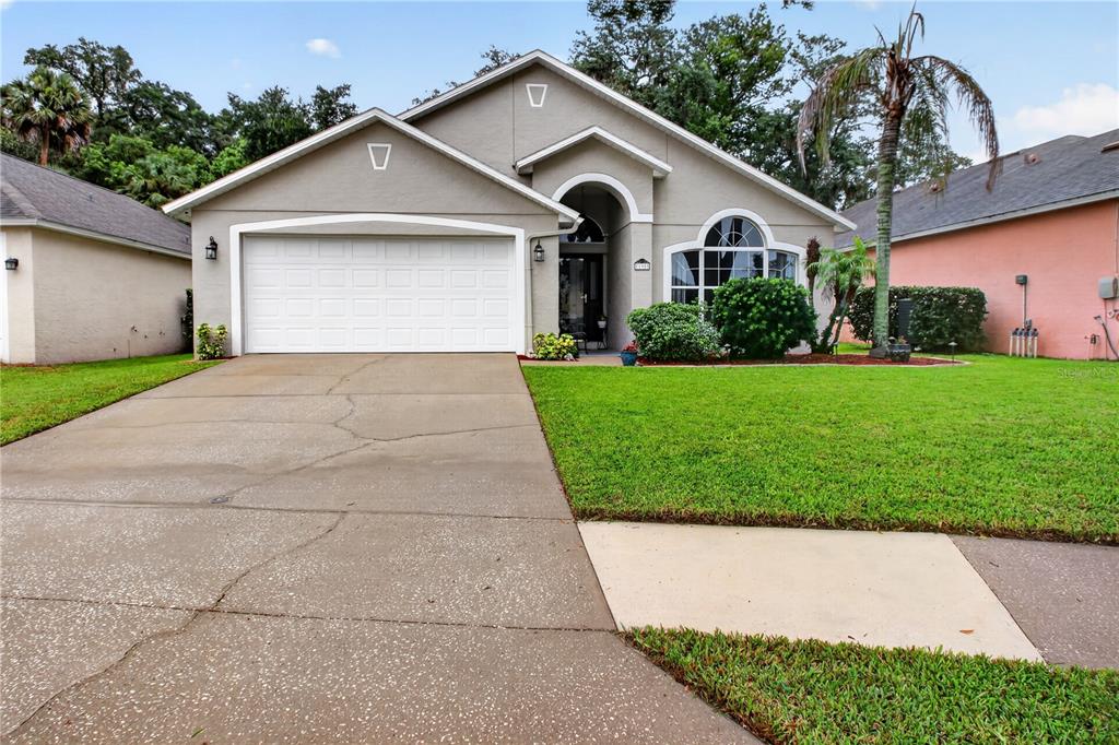 A single-story suburban house with a two-car garage, arched entryway, and a concrete driveway — 195 BRUSHCREEK DRIVE, SANFORD, FL