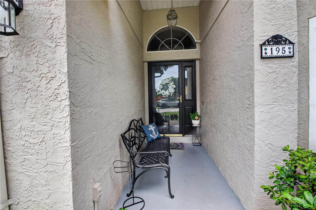 A covered entryway features a black metal bench, a glass-paneled front door, and a house number — 195 BRUSHCREEK DRIVE, SANFORD, FL