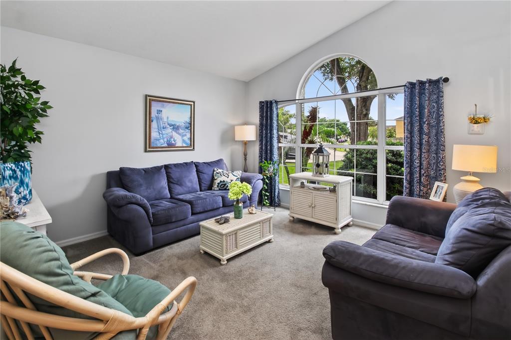 A living room features two blue sofas, a rattan chair, and a large arched window — 195 BRUSHCREEK DRIVE, SANFORD, FL