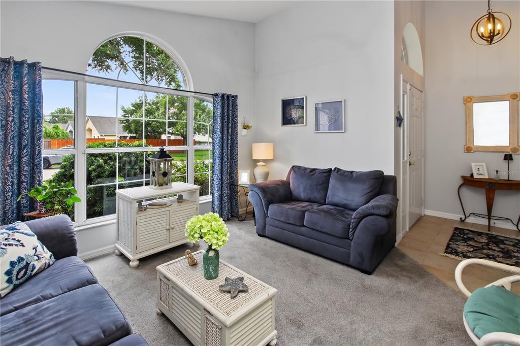 A living room features gray sofas, a white coffee table, and a large arched window — 195 BRUSHCREEK DRIVE, SANFORD, FL