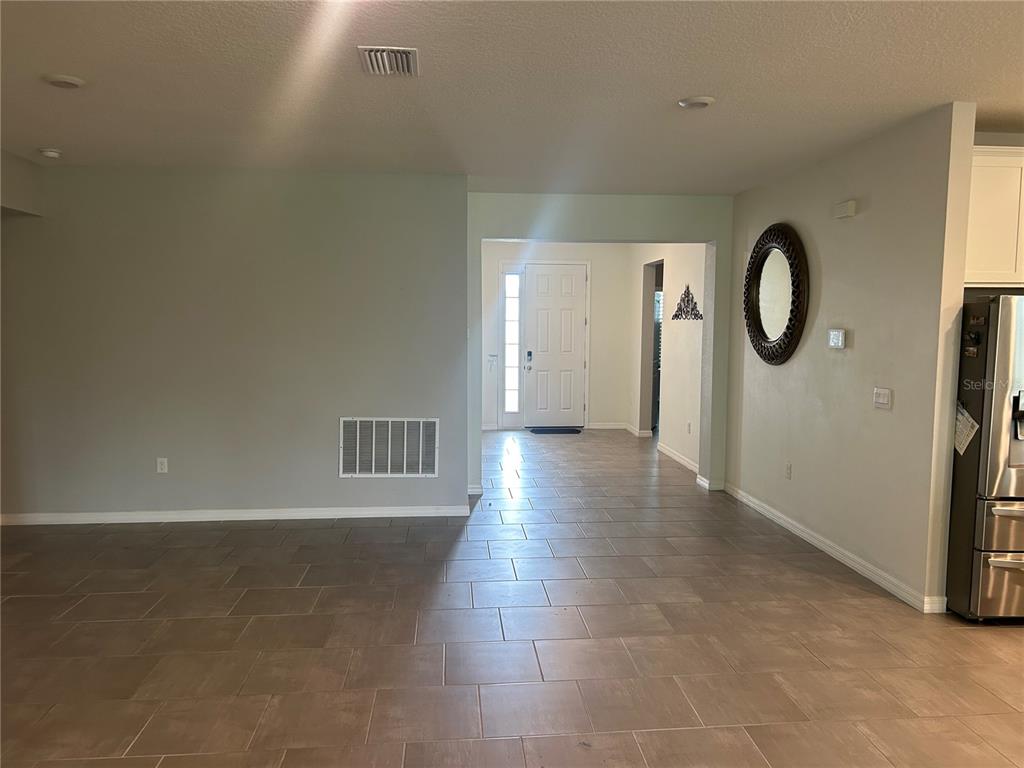 A view from a tiled living area looking toward the home's front entryway and door — 7128 STEER BLADE DRIVE, ZEPHYRHILLS, FL