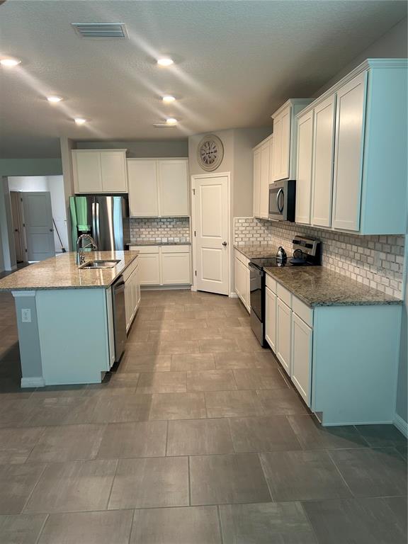 A kitchen features white cabinets, granite countertops, a center island, and light-colored tile flooring — 7128 STEER BLADE DRIVE, ZEPHYRHILLS, FL